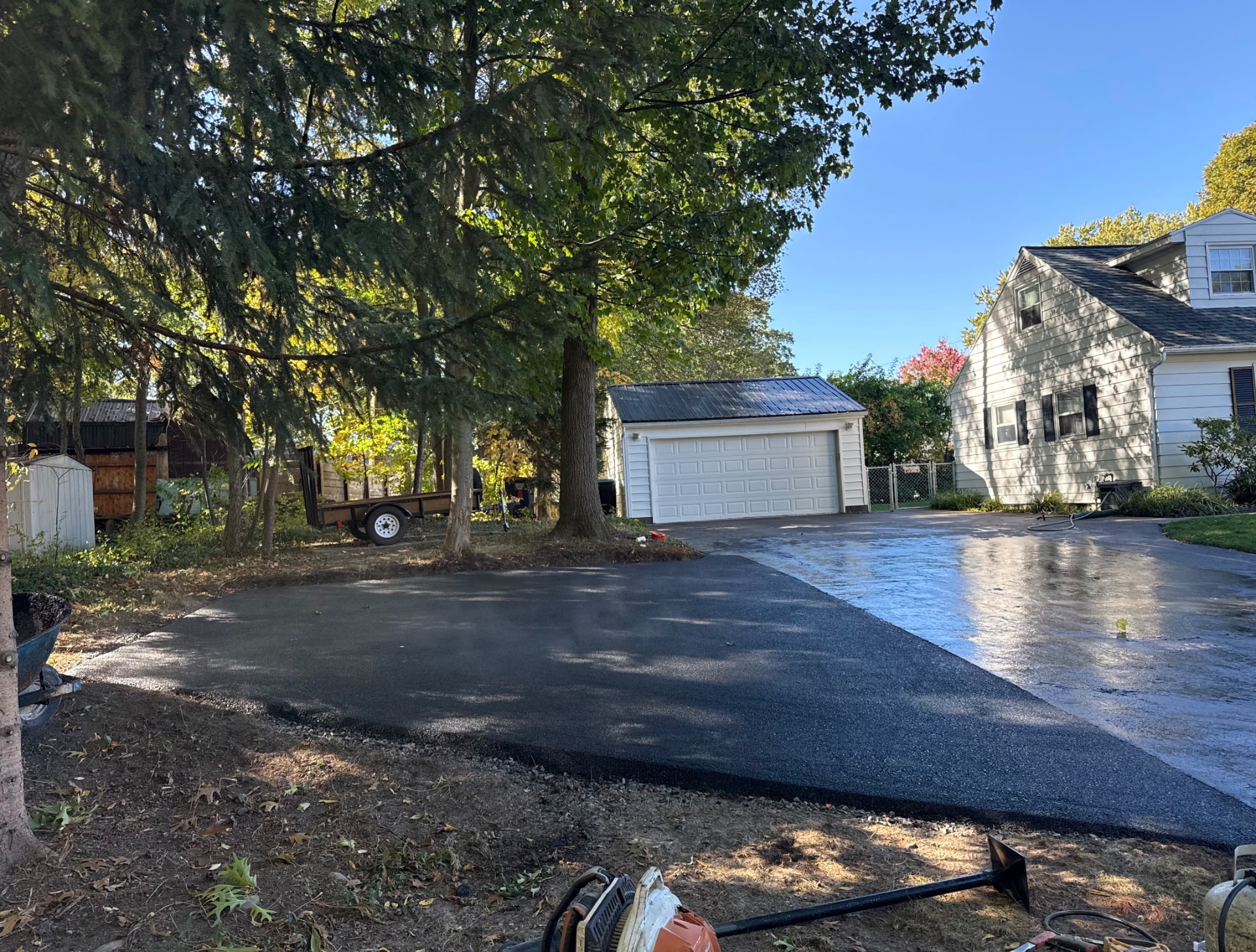 New asphalt driveway leading to a detached garage