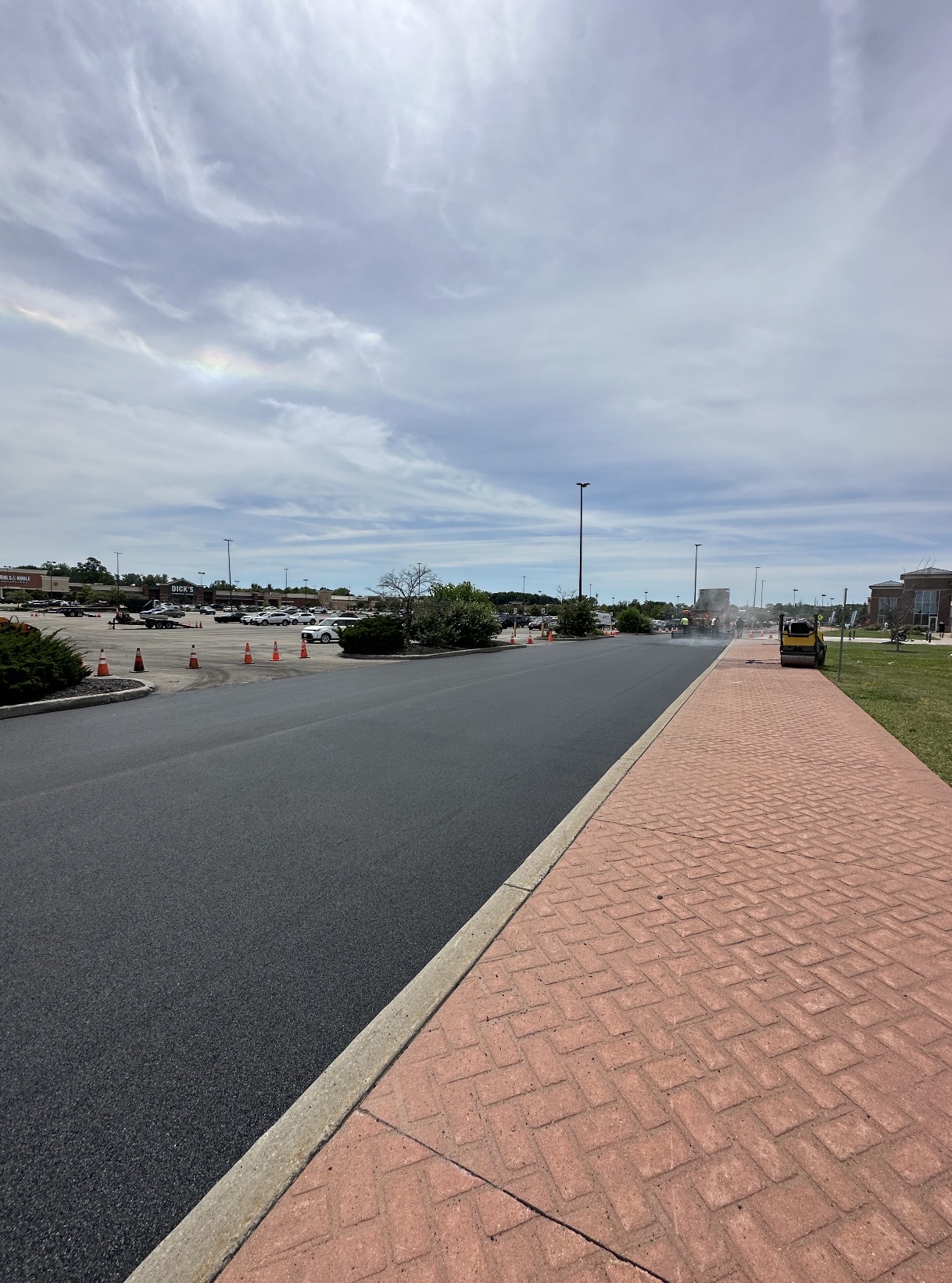 Freshly paved plaza drive lane with roller finishing the mat