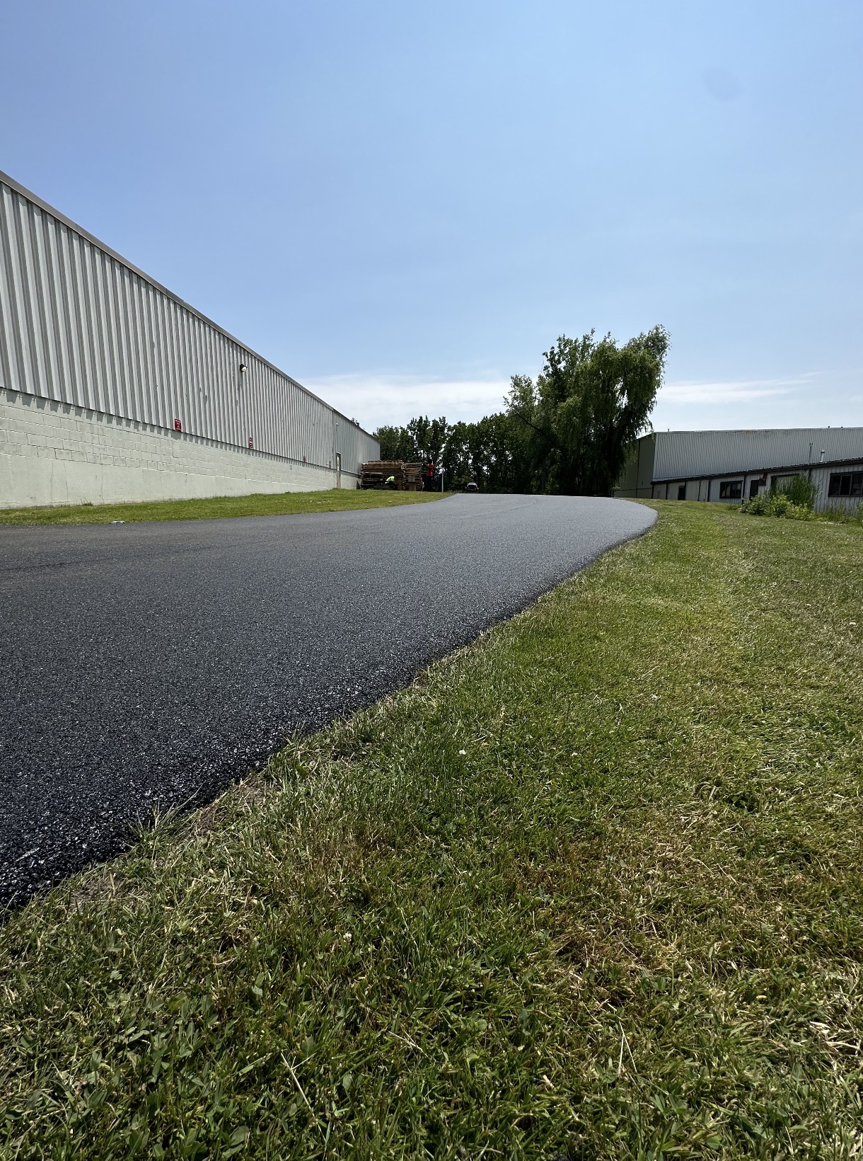 Freshly paved commercial access road beside a warehouse building