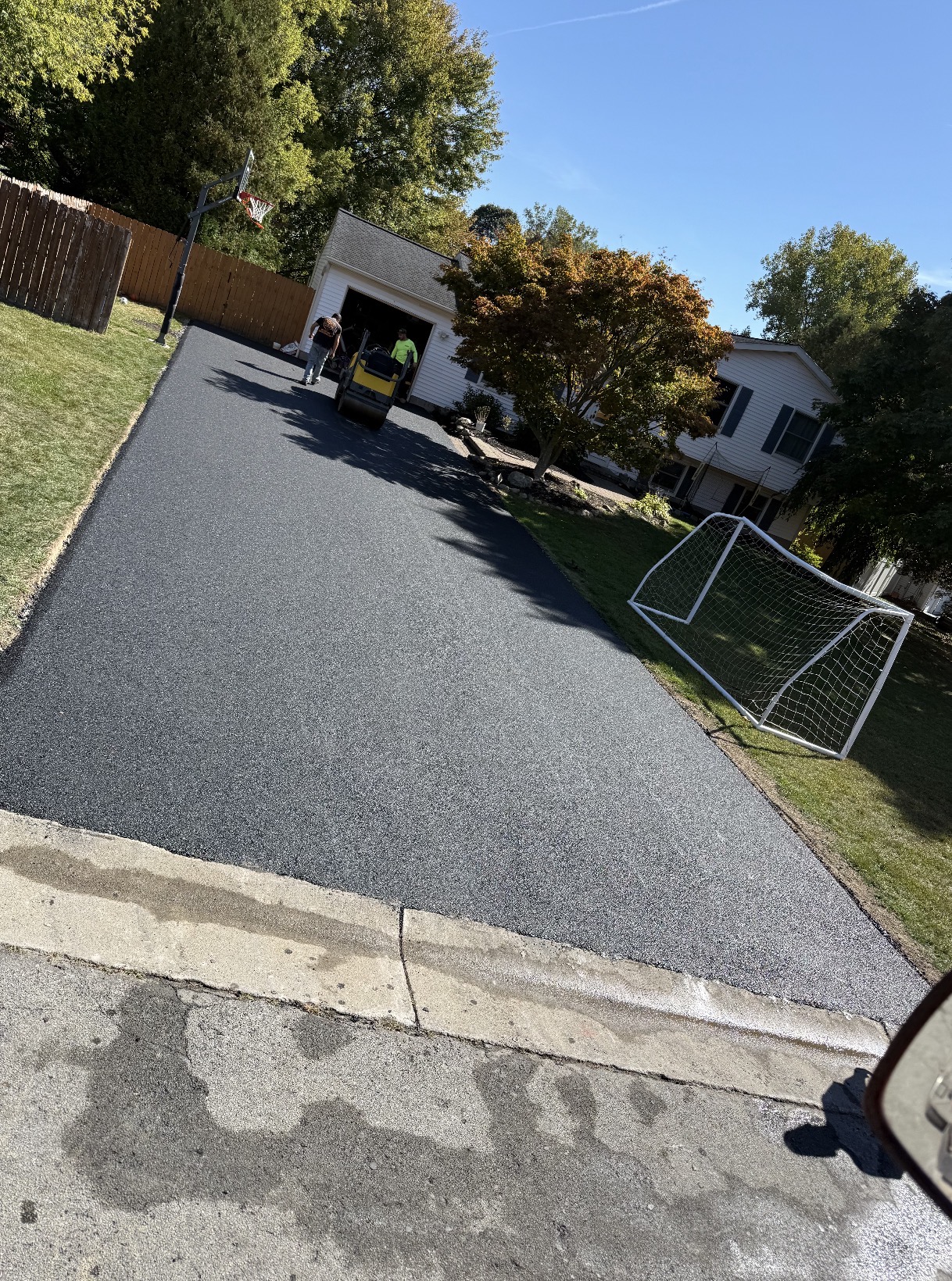 Freshly paved residential driveway being compacted with a roller