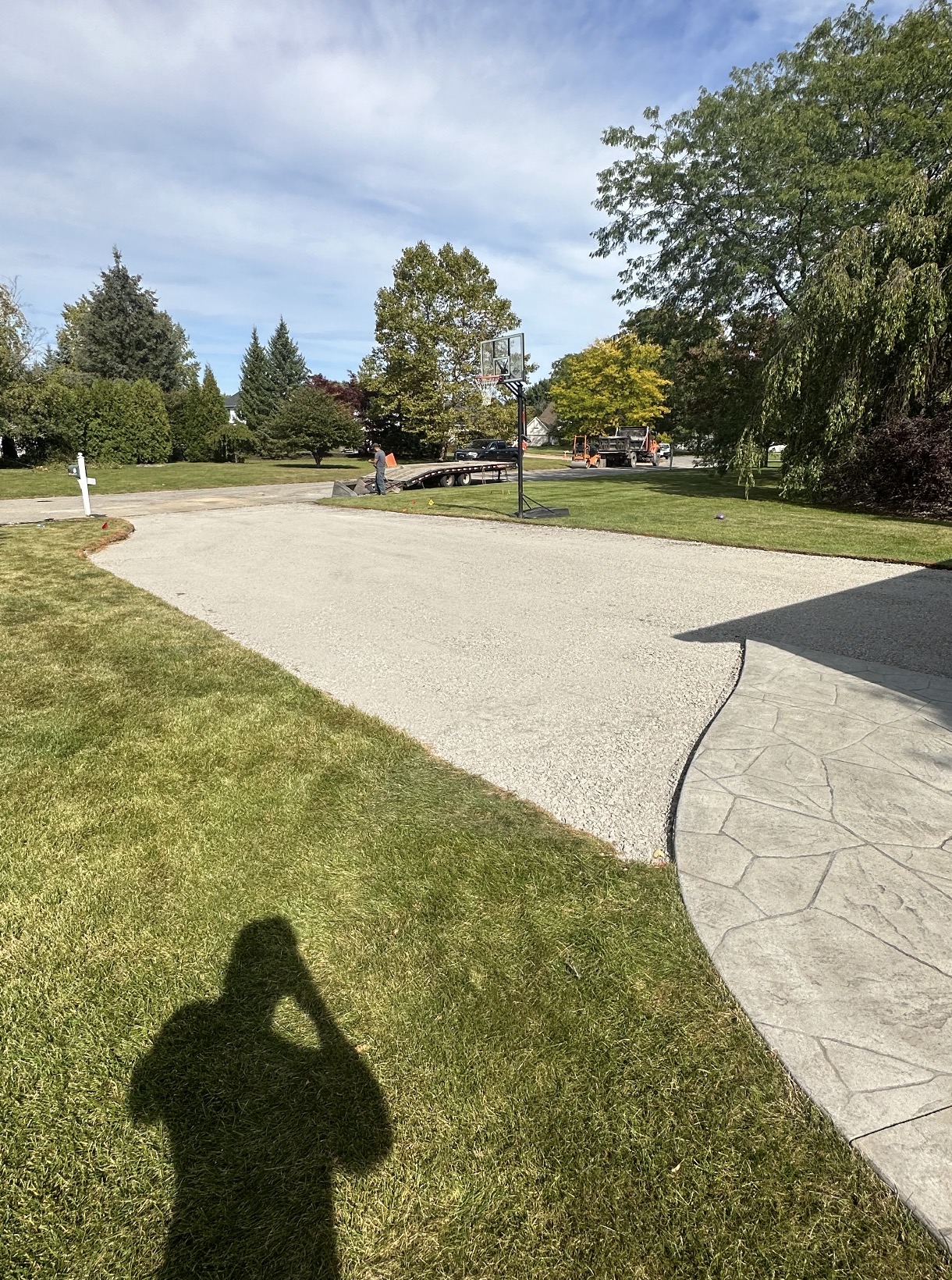 New stone driveway base beside a stamped concrete apron