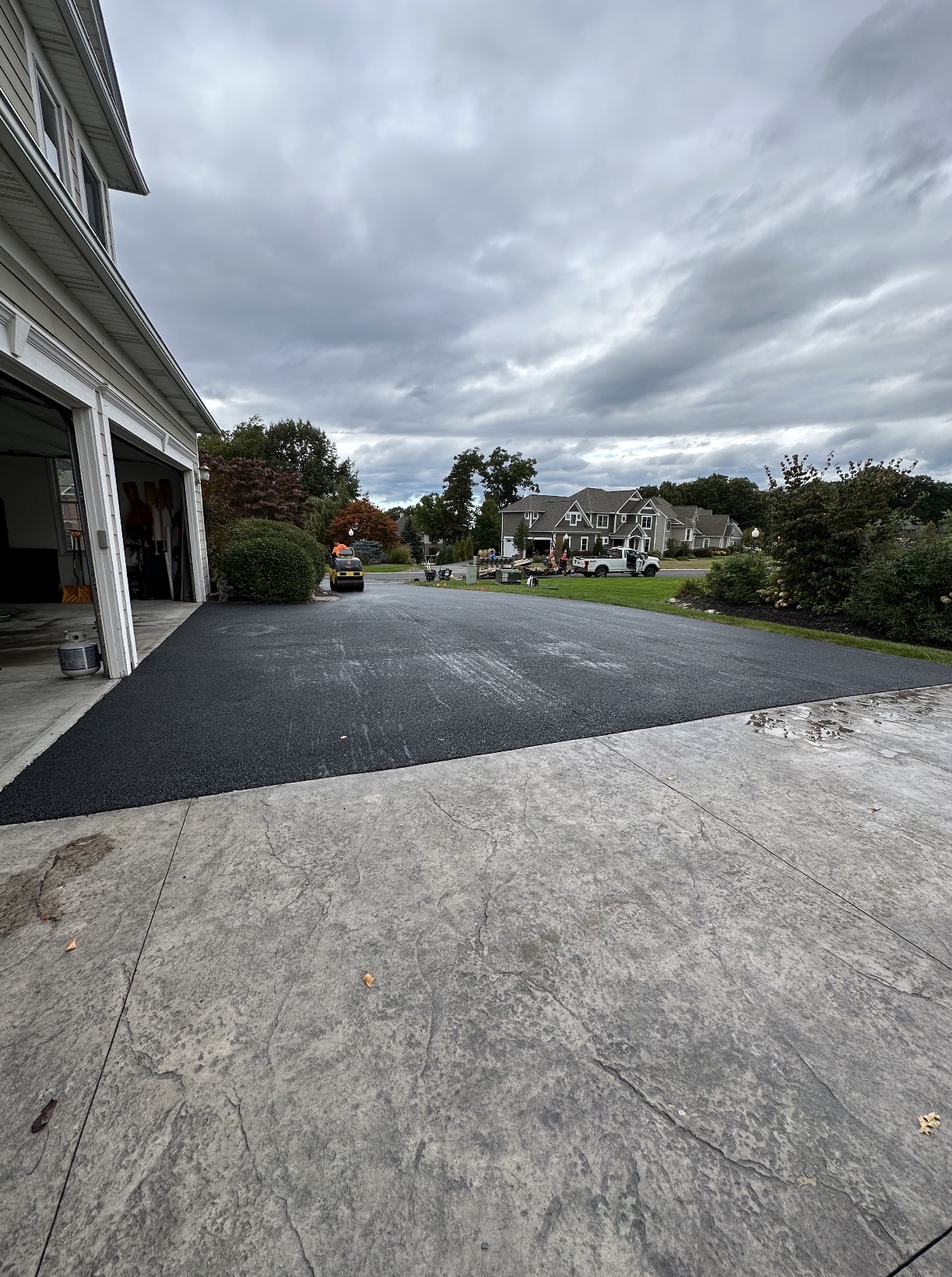 Wide new asphalt driveway meeting a stamped concrete apron